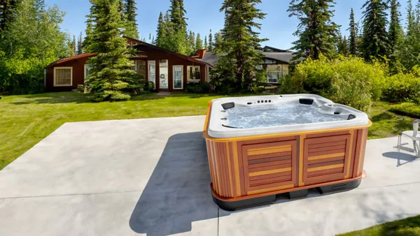 Arctic Spas Yukon on a deck surrounded by greenery at dusk