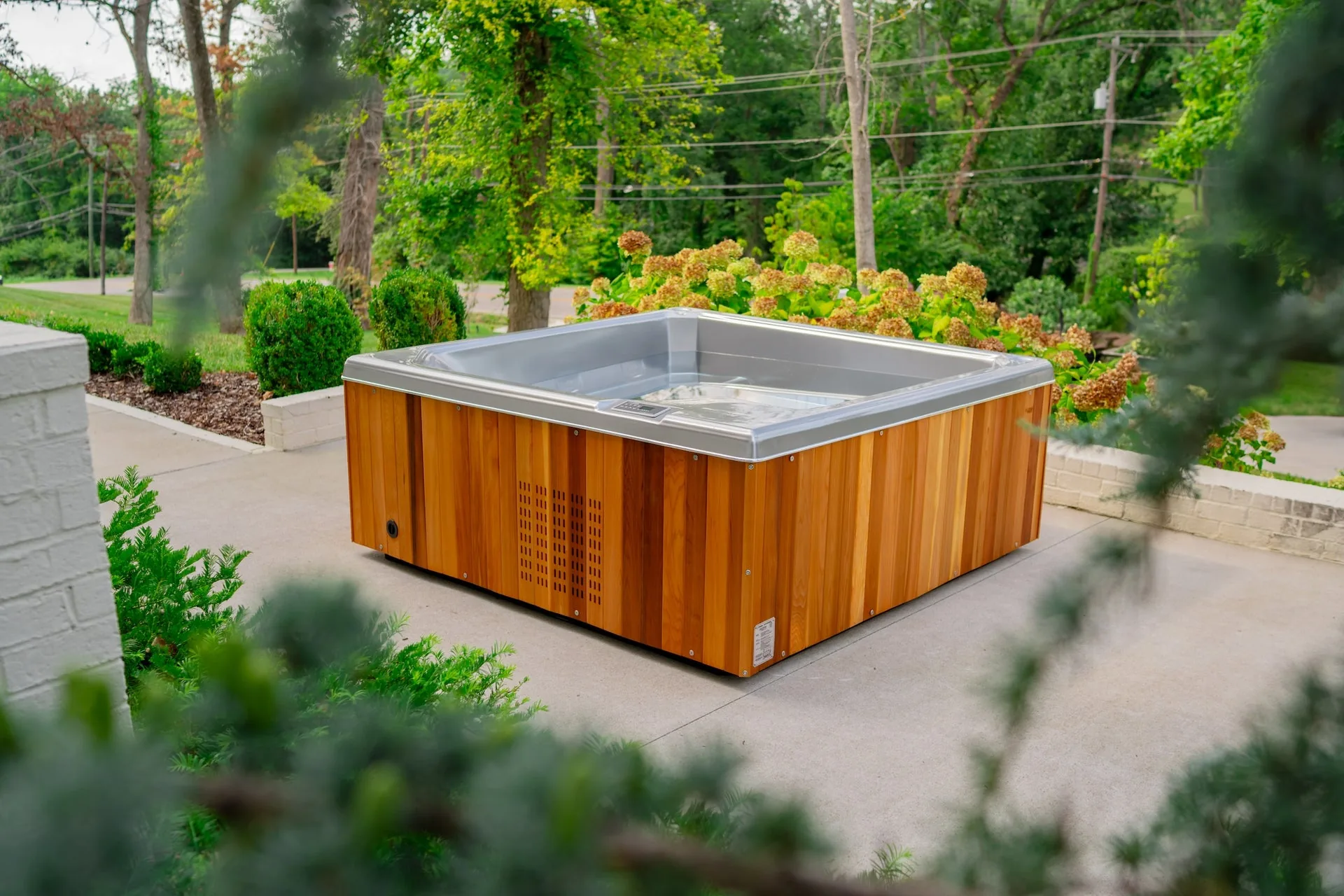 Icebox square cold plunge tub with bathers on a wooden deck surrounded by palms