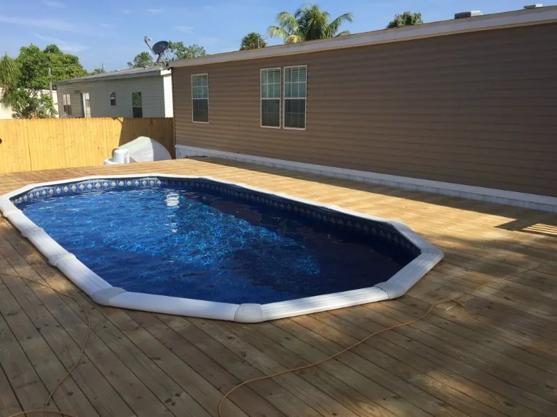 Oval aboveground pool set into a timber deck beside a South Florida home