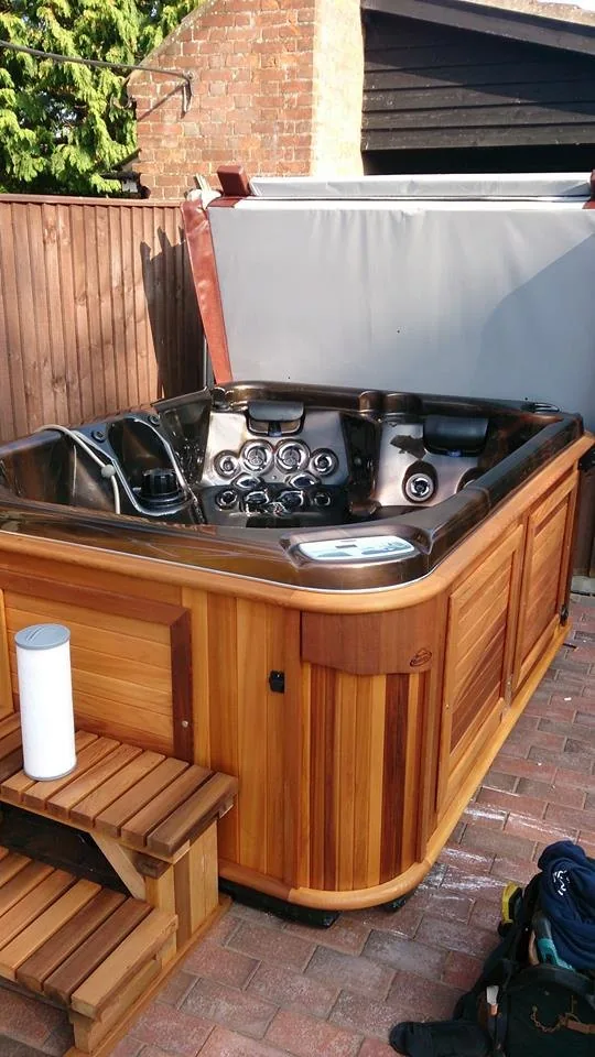 Compact hot tub tucked into a small paved courtyard beside a modern townhouse