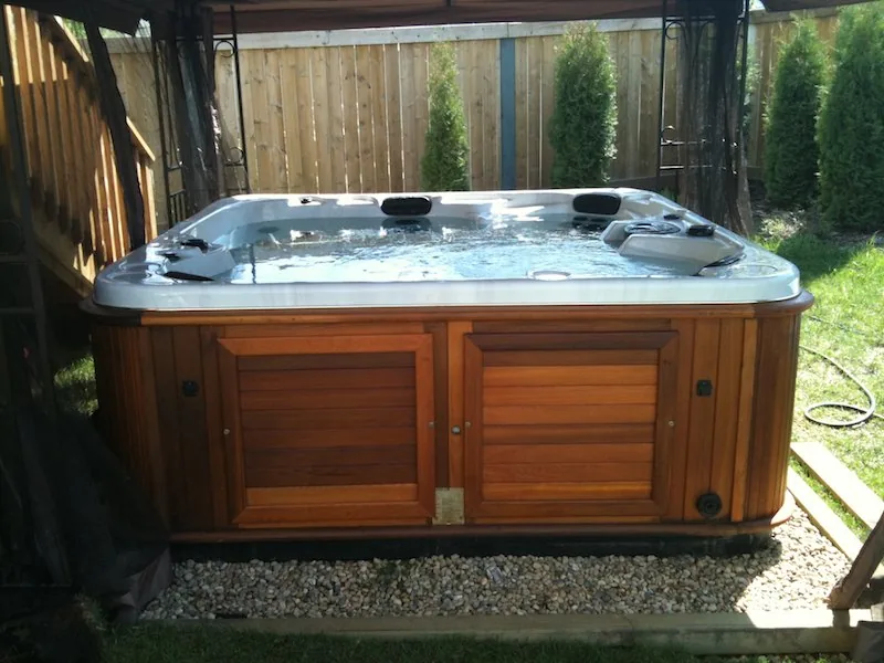Technician testing hot tub water chemistry during a scheduled maintenance visit